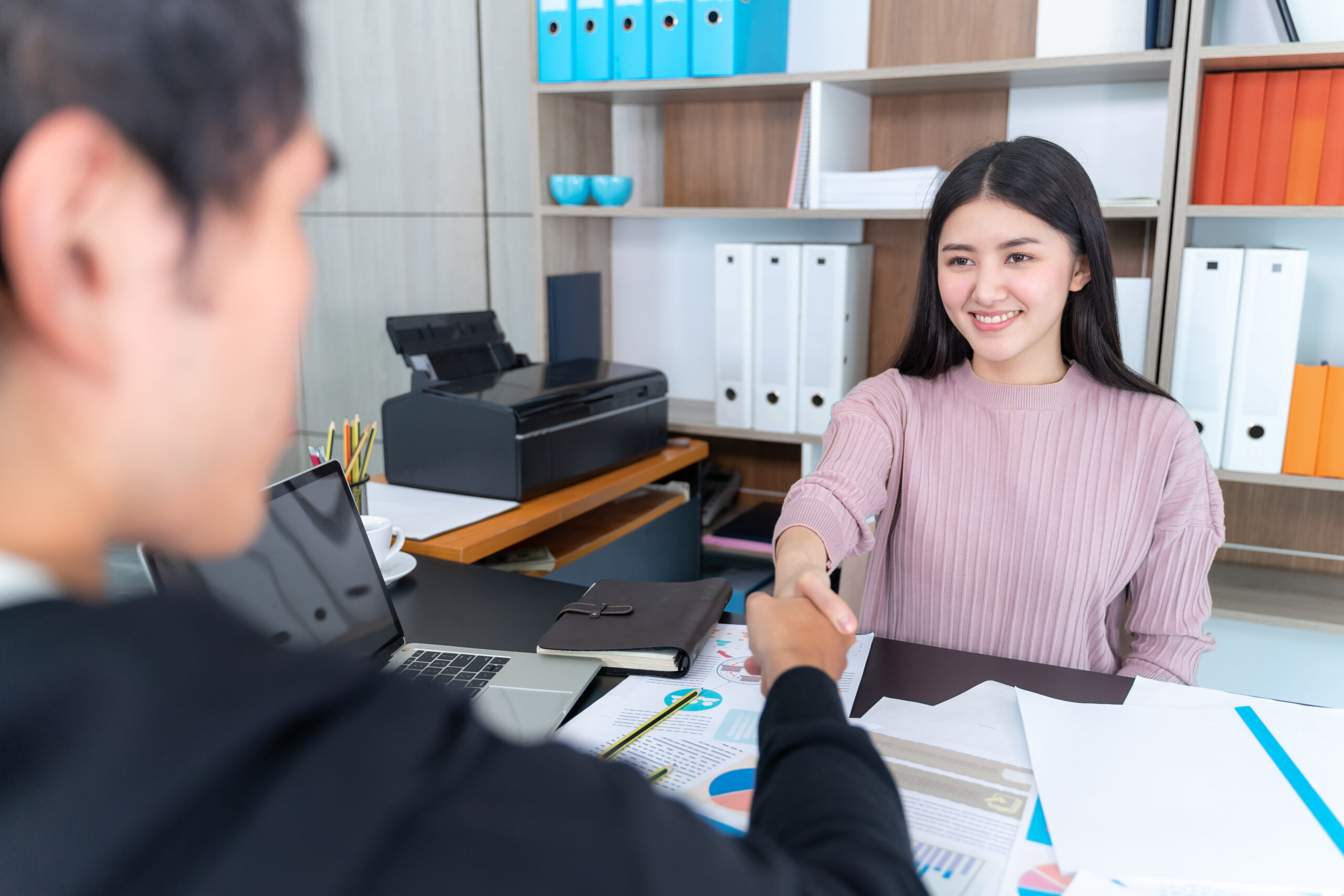 Young working woman check hands with businessman